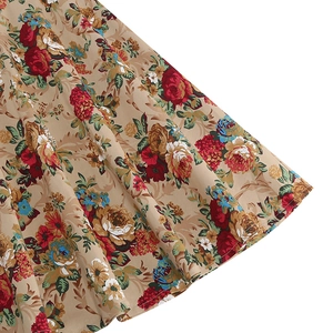 Close-up of vintage khaki floral fabric with red roses and yellow flowers on a skirt