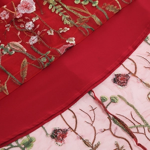 Detail of red vintage skirt showing delicate pink floral embroidery and layered mesh fabric