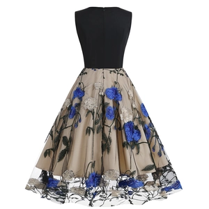 Detail of elegant vintage dress showing blue floral embroidery on champagne mesh fabric