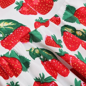 Detail of red strawberry print on white cotton fabric with pleated smocking technique