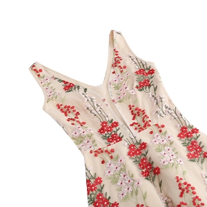 Detailed close-up of intricate red and pink floral embroidery on beige tulle dress V-neck