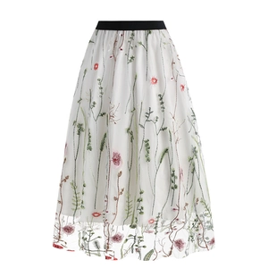 Detail of white mesh skirt featuring colorful floral embroidery and black elastic waistband