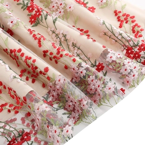 Detailed view of red and pink floral embroidery on beige mesh tulle evening dress