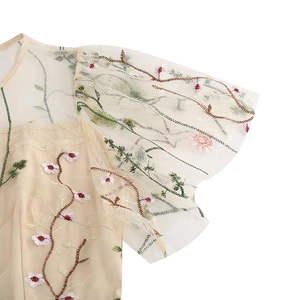 Detail of floral embroidery on sheer mesh sleeves of a vintage champagne party dress