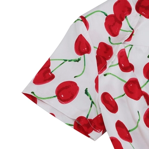 Detailed view of the V-neckline and sleeve with vibrant red cherry print on white fabric