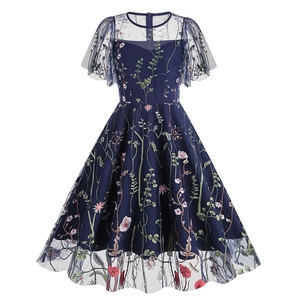 Detailed view of dark blue dress featuring heavy floral embroidery and mesh sleeves