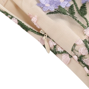 Detail of floral embroidery and invisible zipper on apricot V-neck evening dress