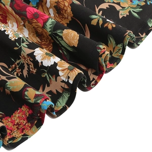 Close-up detail of vintage floral print fabric with layered ruffle hem on black skirt