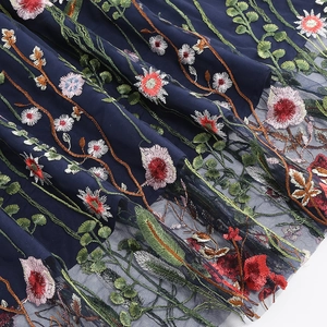 Detail of multi-color floral embroidery on dark blue mesh tulle fabric for skirt