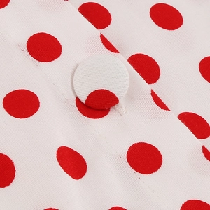Detailed close-up of white fabric with red polka dots and matching cloth-covered button