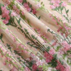 Close-up of intricate floral embroidery on nude mesh fabric for retro party dress