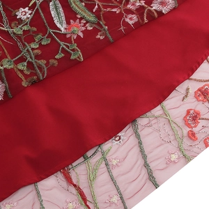 Macro shot of colorful floral embroidery on red mesh fabric of the vintage dress