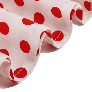 Close-up of vintage red polka dot fabric texture with fine hem stitching on a white dress