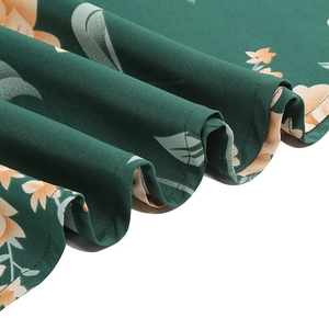 Detailed close-up of dark green floral fabric with orange blossoms and fine stitching