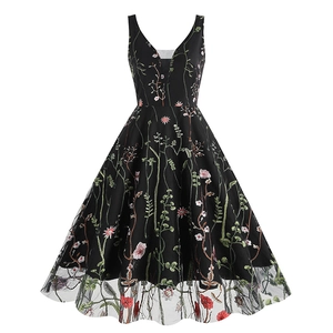 Detailed close-up of colorful floral embroidery and mesh hem on black V-neck dress
