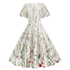 Close-up of floral embroidery detail on a white tulle vintage dress with green leaves