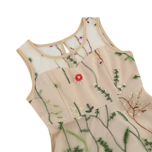 Detail van elegante beige jurk met verfijnd mesh-patchwork en geborduurde bloemen
