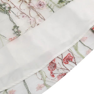 Close-up of intricate floral embroidery on white sheer mesh fabric for vintage dress