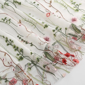Detailed macro view of colorful floral embroidery on high-quality white mesh fabric