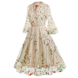Detail of floral embroidery on mesh fabric with elegant bow neckline and flare sleeves