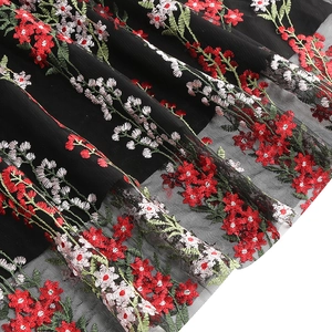 Close-up of vintage floral embroidery on black mesh fabric with red and white flowers
