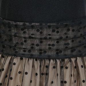Detail of the waist design showing layered black polka dot mesh over a beige tulle skirt