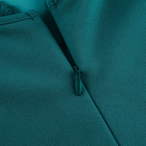 Detailed macro view of invisible zipper and black lace stitching on dark teal dress
