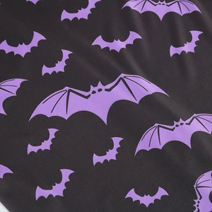 Close-up of Halloween V-neck dress fabric with purple bat prints on black background