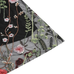 Detailopname van ingewikkelde rode bloemenborduur op zwart gaas en tule materiaal