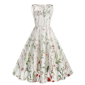 Detailed view of intricate green vine and floral embroidery on white mesh fabric