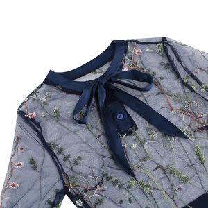 Detail of dark blue mesh dress showing colorful floral embroidery and satin bow neckline