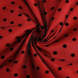 Detailed macro view of red mesh fabric with black velvet polka dots and elegant draping