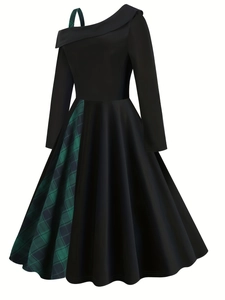 Detail of cold-shoulder dress showing asymmetric green plaid strap and black fabric