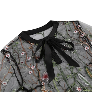 Detail of gothic dress showing floral embroidery on black mesh with a satin bow neckline