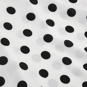 Macro shot of retro white chiffon fabric with classic black polka dots and fine texture