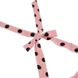 Detail of pink polka dot chiffon dress featuring a stylish waist tie knot on white background