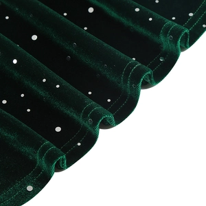Détail du tissu en velours vert foncé avec paillettes argentées et bord d'ourlet