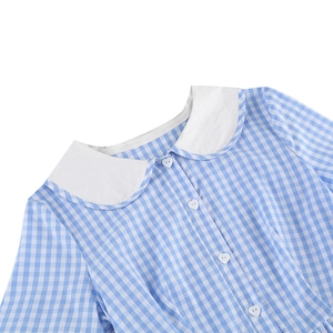 Détail de robe à carreaux bleus avec col Claudine blanc et boutons en cœur