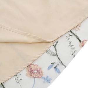 Close-up of floral embroidery on delicate white mesh and beige fabric dress hem