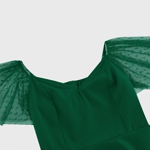 Close-up of V-neckline and sheer green mesh puff sleeves with elegant polka dot texture