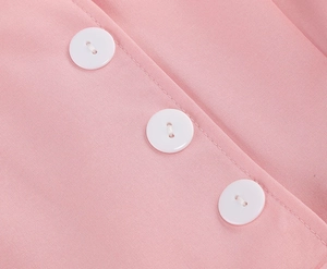 Detailed view of white buttons and twill fabric texture on a pink summer dress