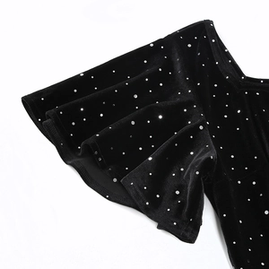 Détail de la robe en velours noir à pois argentés avec col en V et manches à volants
