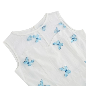 Detail of white vintage dress showing 3D blue butterfly embroidery and wavy texture