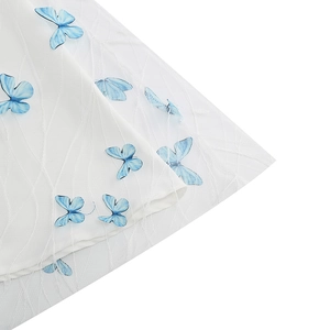 Close-up of 3D blue butterfly appliqués with embroidery on white mesh dress fabric