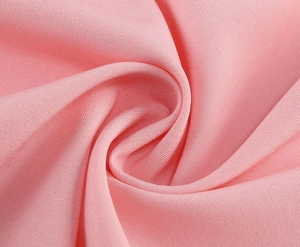 Macro shot of smooth pink woven fabric texture with artistic spiral pleats and soft lighting