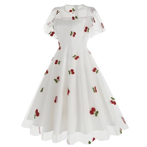Gros plan détaillé du tissu en maille blanche avec broderies de cerises rouges sur robe