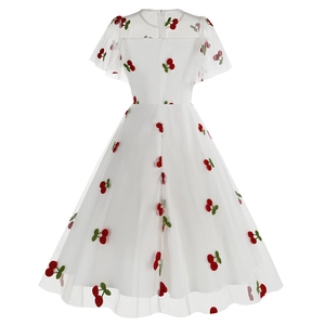 Détail de la broderie cerise rouge sur le tissu en tulle blanc de la robe trapèze