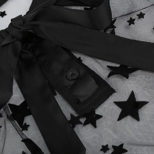 Detail showing black mesh dress with velvet stars, satin bow and single button closure