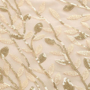 Detail of golden sequin leaf embroidery on champagne mesh fabric for evening dress