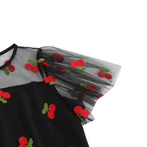 Détail de robe noire en mesh avec broderie cerise exquise et manches à volants